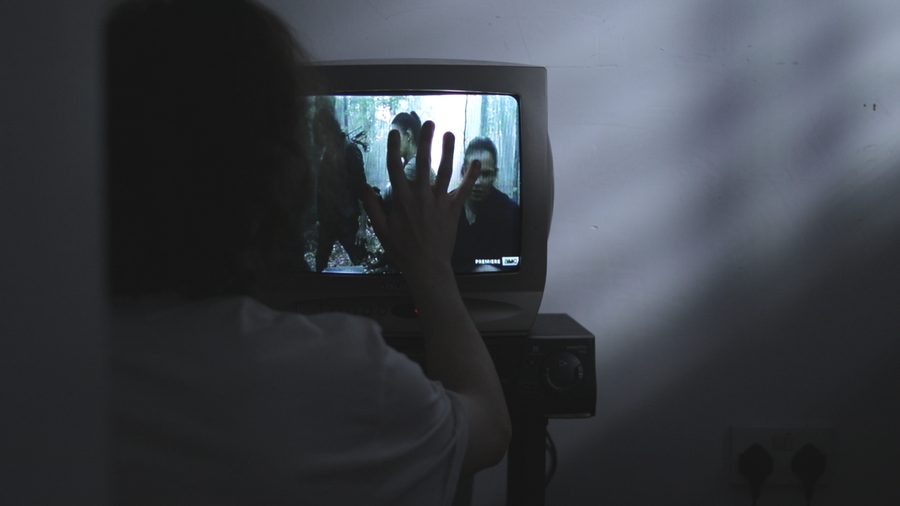 A hand pressed against the screen of an old television